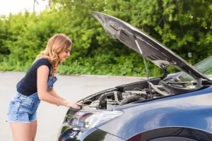 車のボンネットを開く女性